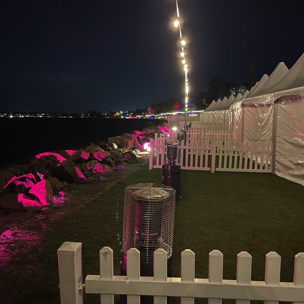 Tents setup along the waterfront for Food and Wine Festival. There are rocks along the shore that have been lit in pink. Live event audio Brisbane, Gold Coast, Sunshine Coast